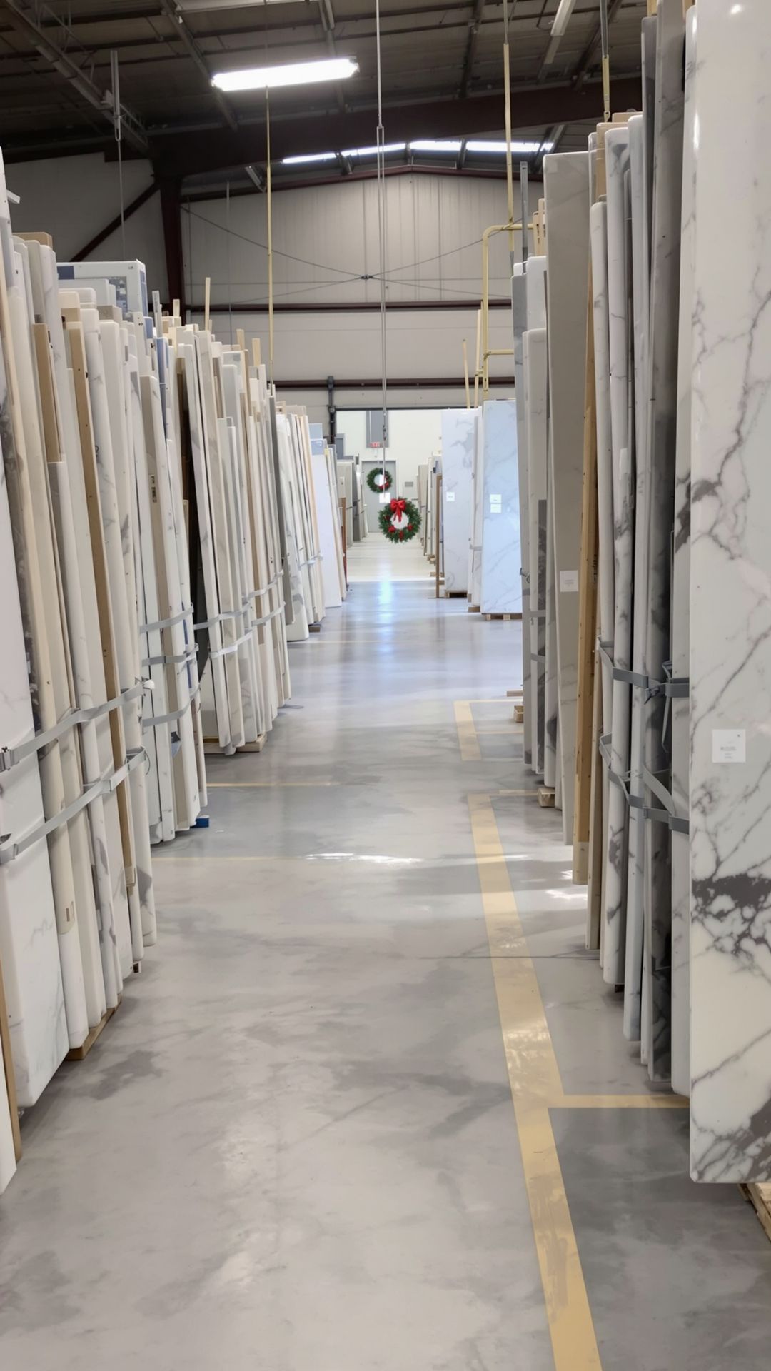 Warehouse preparing for holiday shutdown with countertop slabs secured, straps tightened, and aisles cleared.